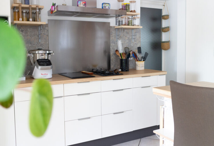Vue d’ensemble d’un home staging cuisine montrant une cuisine blanche et bois rénovée, ouverte sur le salon et intégrée harmonieusement à l’espace de vie.