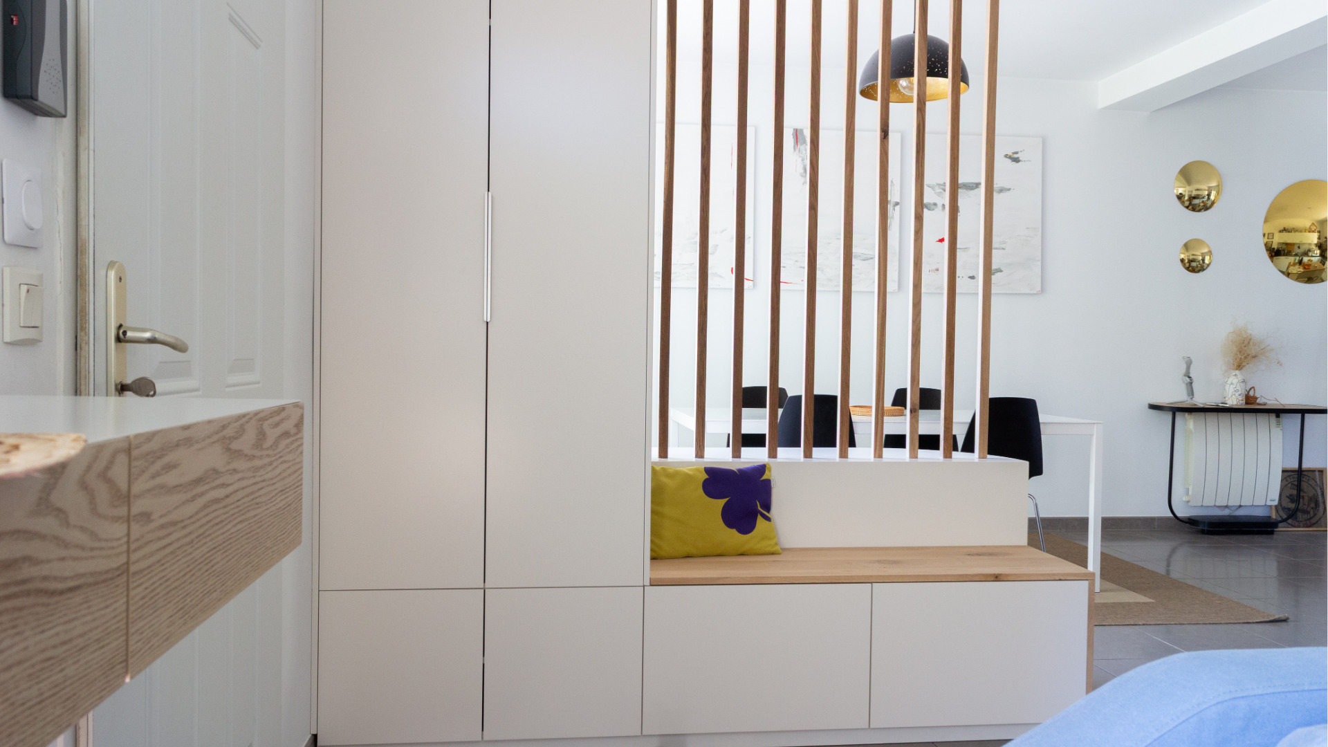 Vue d’ensemble d’un meuble d’entrée sur mesure depuis le séjour, comprenant un banc intégré, des rangements fermés et un claustra ajouré structurant l’espace.