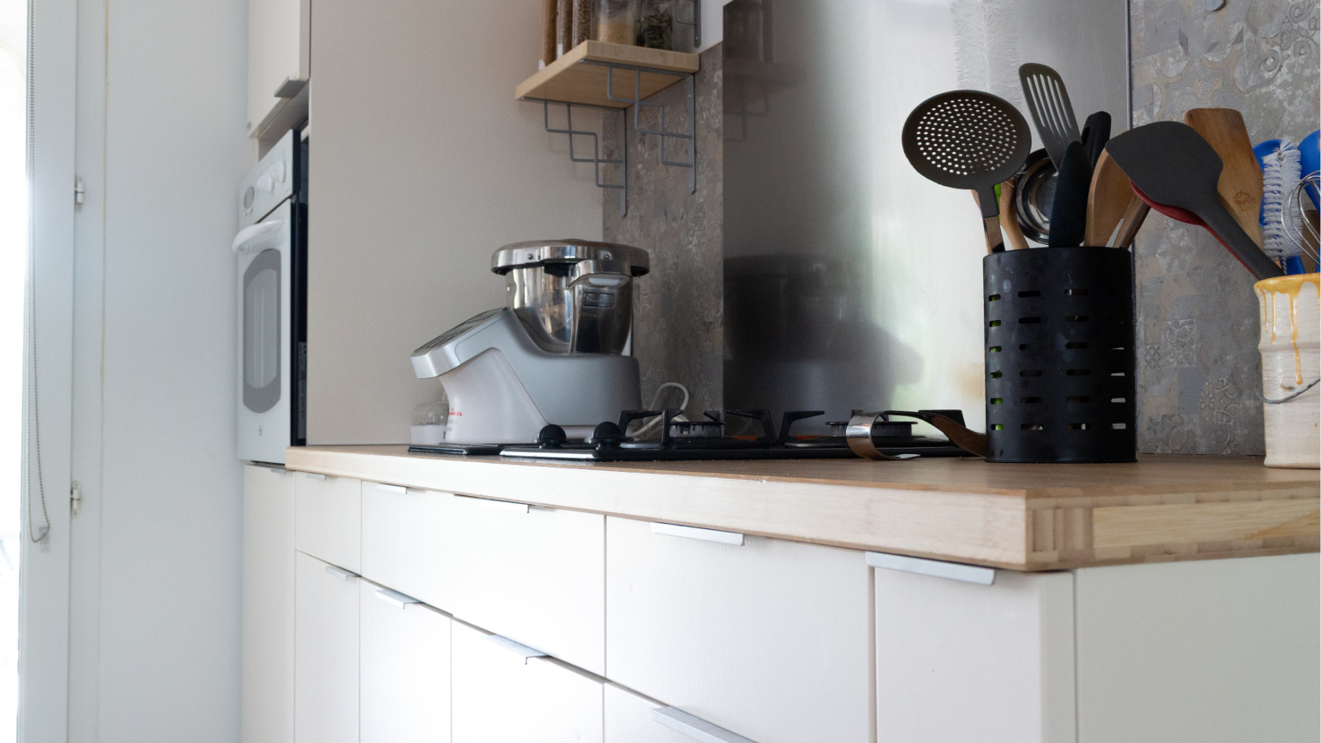 Gros plan sur un home staging cuisine avec façades repeintes, mettant en valeur les plaques de cuisson intégrées dans un ensemble modernisé.