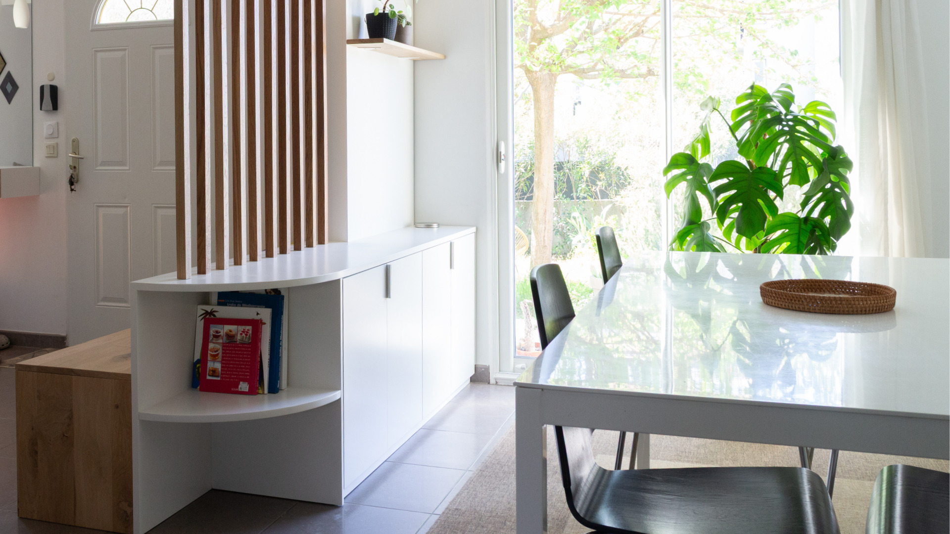 Vue du meuble d’entrée sur mesure depuis la salle à manger, montrant la continuité avec la table et le côté buffet intégré aux rangements.