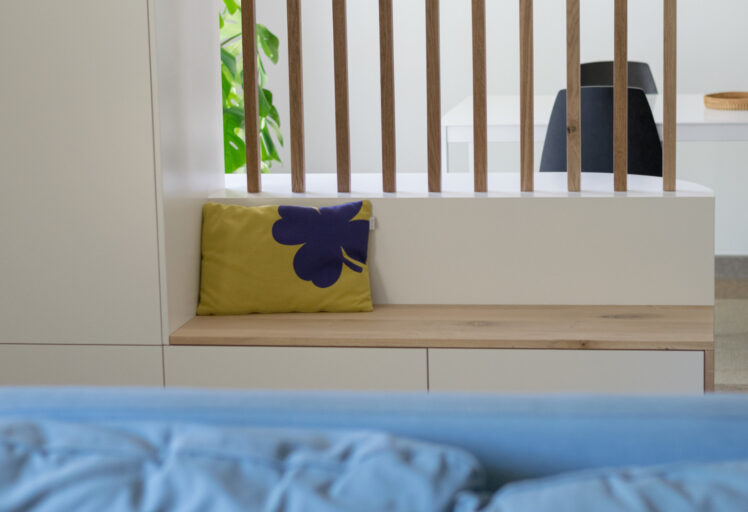 Gros plan sur l’assise du meuble d’entrée sur mesure, avec un banc intégré et un coussin décoratif pour apporter confort et chaleur.