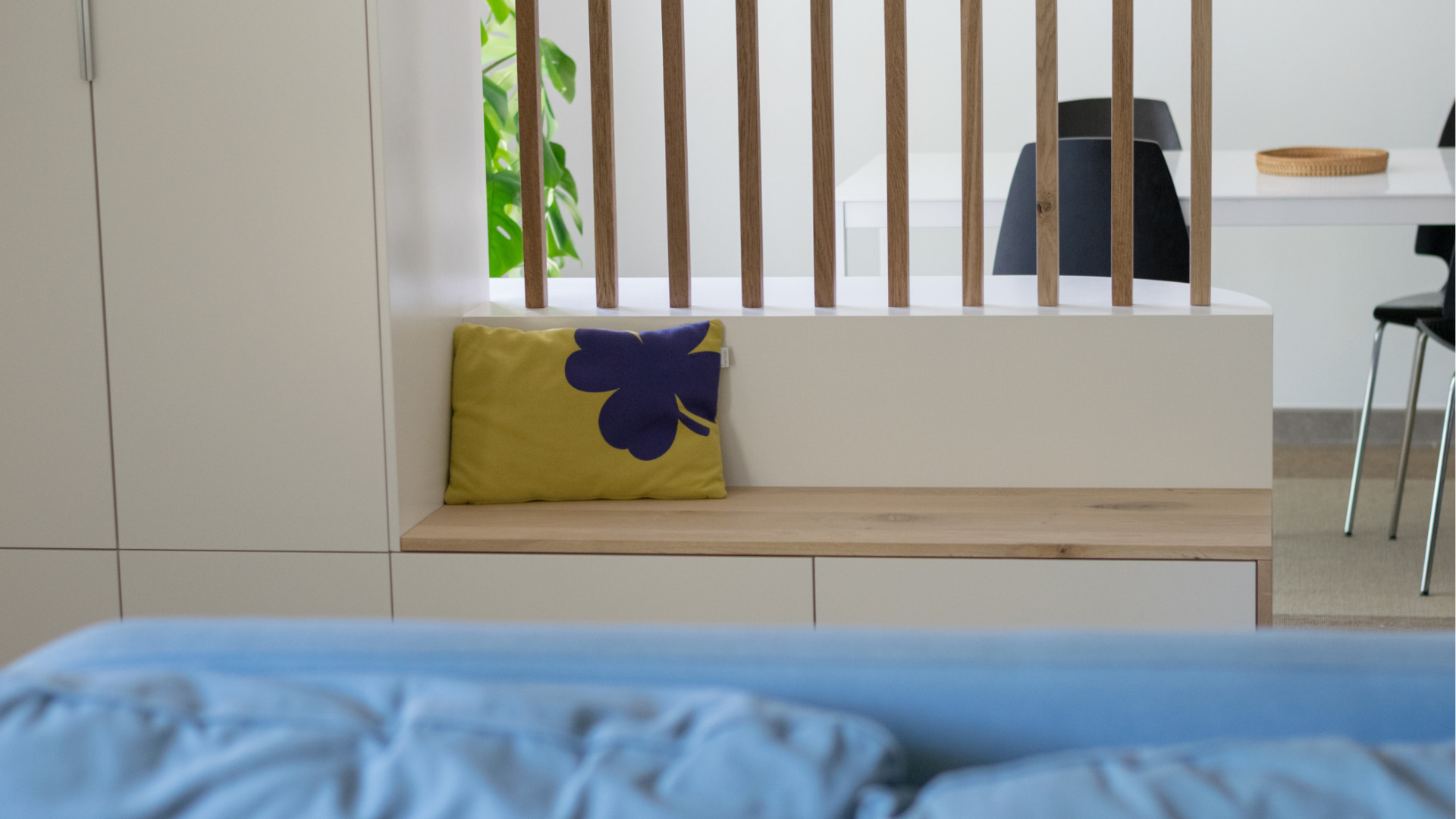 Gros plan sur l’assise du meuble d’entrée sur mesure, avec un banc intégré et un coussin décoratif pour apporter confort et chaleur.