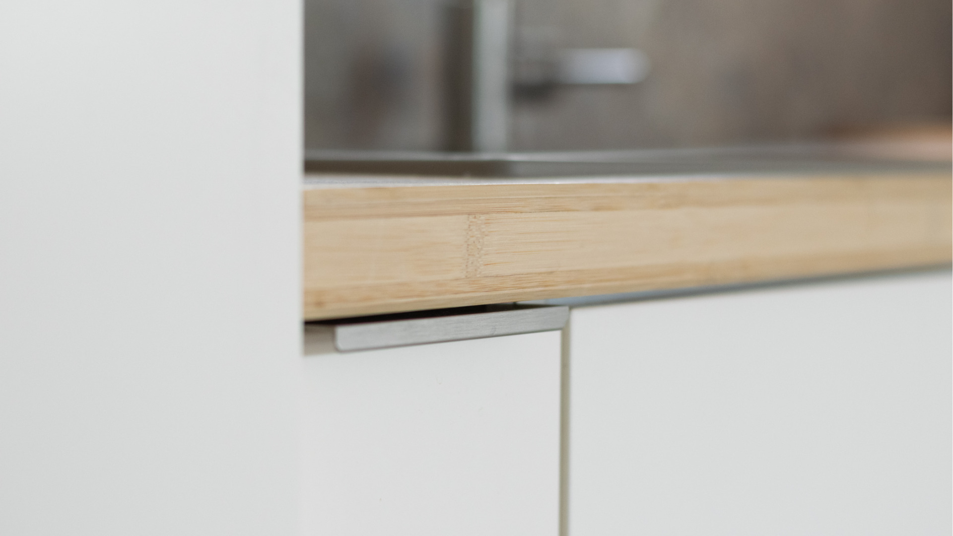 Détail des nouvelles poignées fines et discrètes installées sur les meubles d’une cuisine rénovée pour un rendu minimaliste et contemporain.